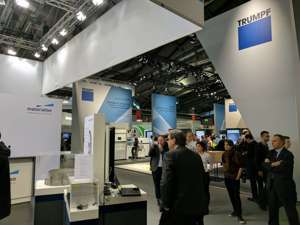 Helmut Zeyn of Siemens Digital Factory Division presenting at Materialise booth during Formnext with Trumpf exhibiting opposite. Photo by Michael Petch.