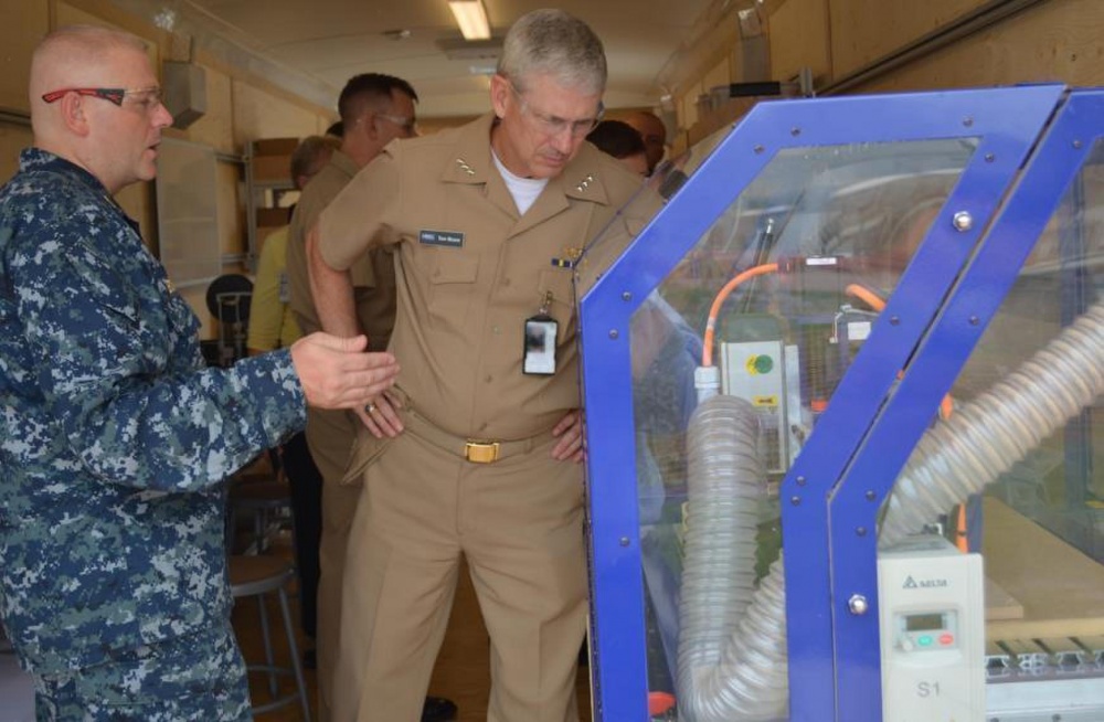 Sean A. Boykin explaining a 3D CNC Router. Photo by Scott Curtis for the US Navy. 