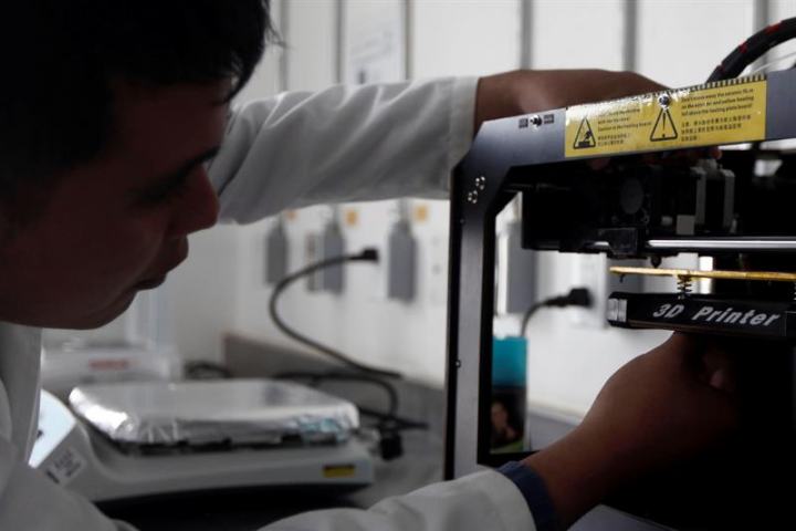 Irving Fernandez tinkering with the laboratory's 3D printer. Photo via EFE. 