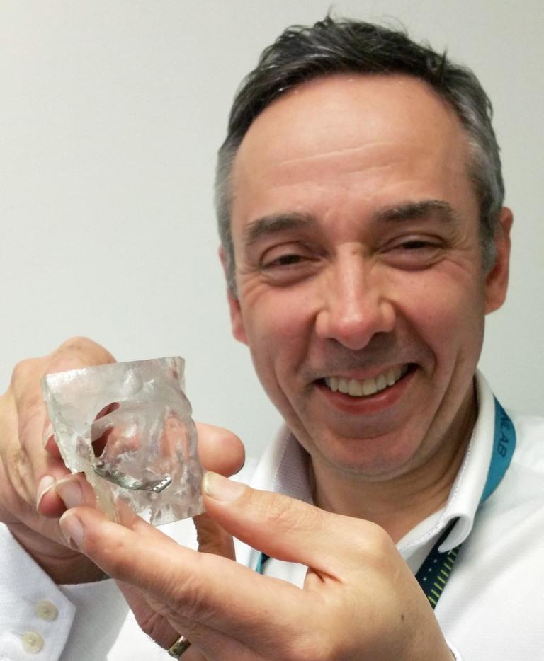 Peter Llewelyn Evans holding a 3D printed implant for an eye socket. Photo via Abertawe Bro Morgannwg University Health Board.