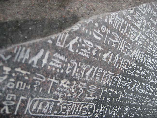 Close up of hieroglyphic script on the Rosetta Stone with chalk added to bring out the definition of the inscription. Photo via The Freeman Institute.