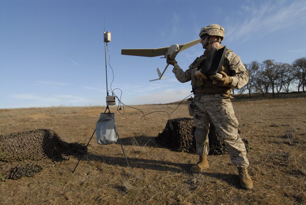 A marine prepares to hand launch a Raven drone/image via Defense Industry Daily