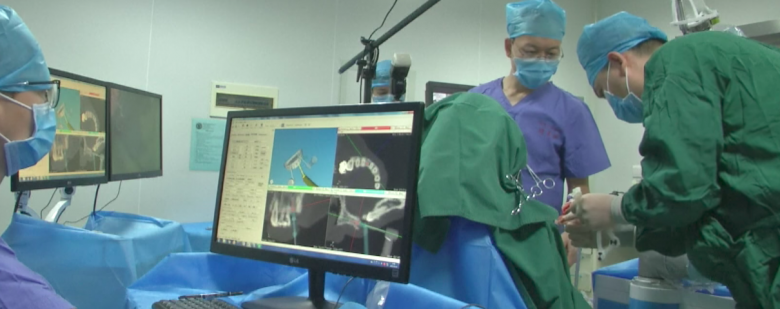 Surgeons monitoring scans and positioning the robot in preparation for surgery. Photo via Youtube/CCTV+.