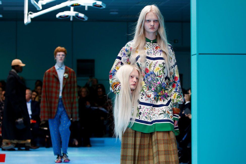 Gucci model Unia Pakhomova carrying a replica of their own head. Photo via Reuters.