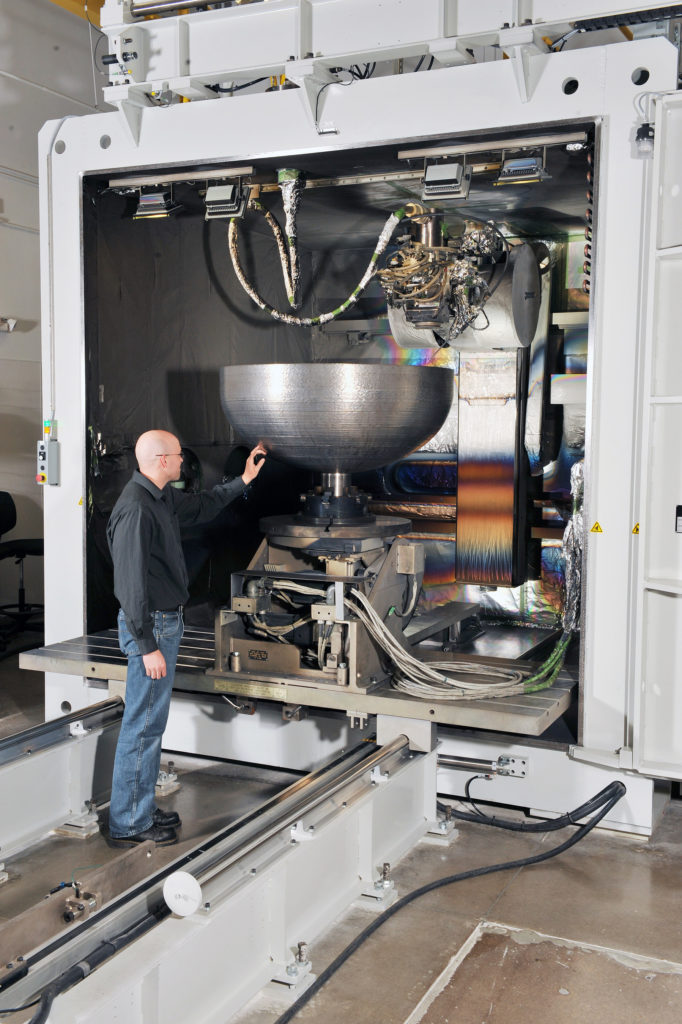 A Lockheed Martin engineer inspects one of the 3D printed dome prototypes at the company's space facility in Denver. The final dome is large enough to fit 74.4 gallons of liquid. Photo via Lockheed Martin.