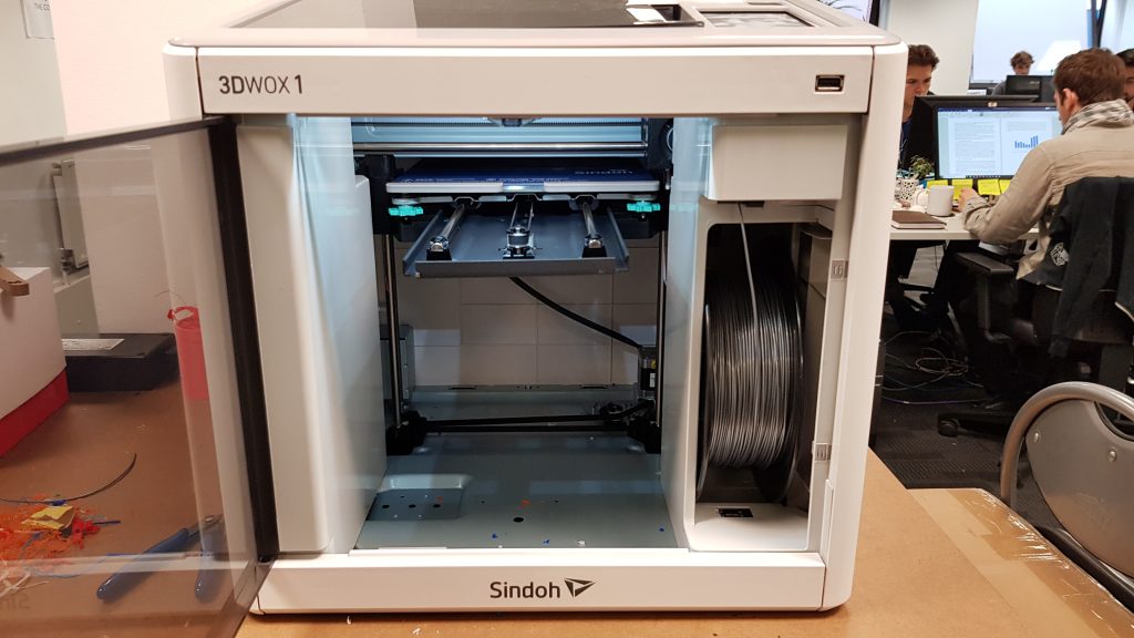 Open front of 3DWOX 1 3D printer showing print bed and material loading slot.