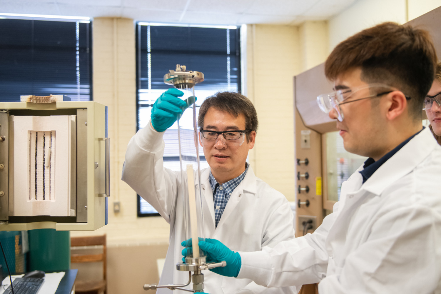 Professor Tong, left, and Ph.D. student Shenglong Mu work in their lab on new technology that combines 3D printing and laser processing. Photo via Clemson University.