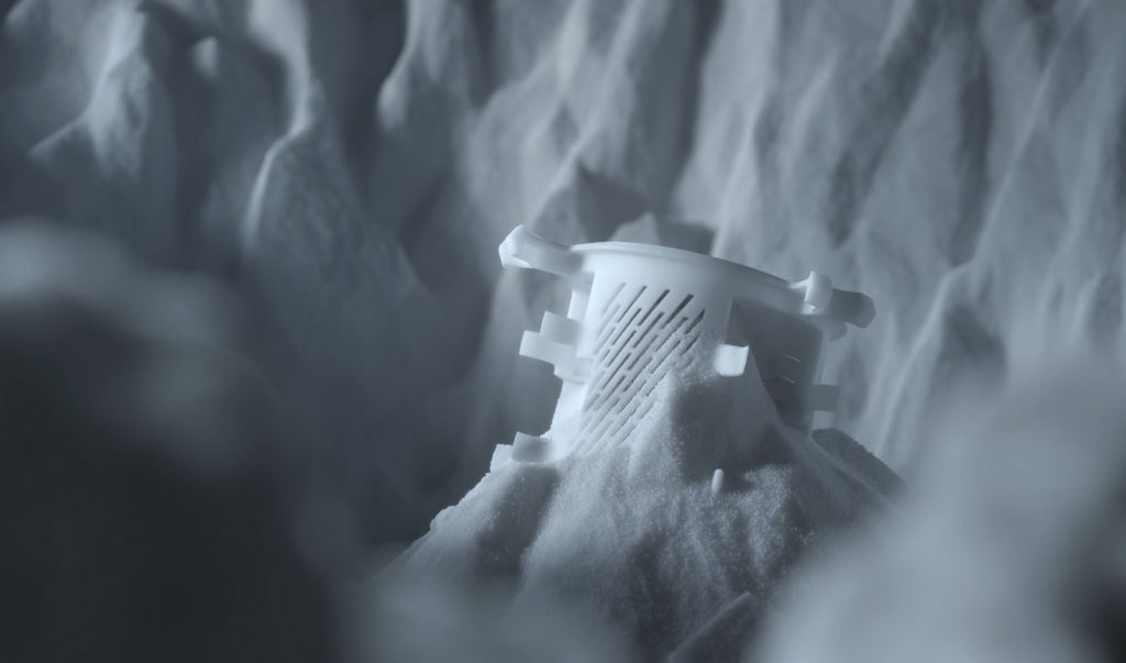 Polymer 3D printed part within the powder bed. Photo via EOS