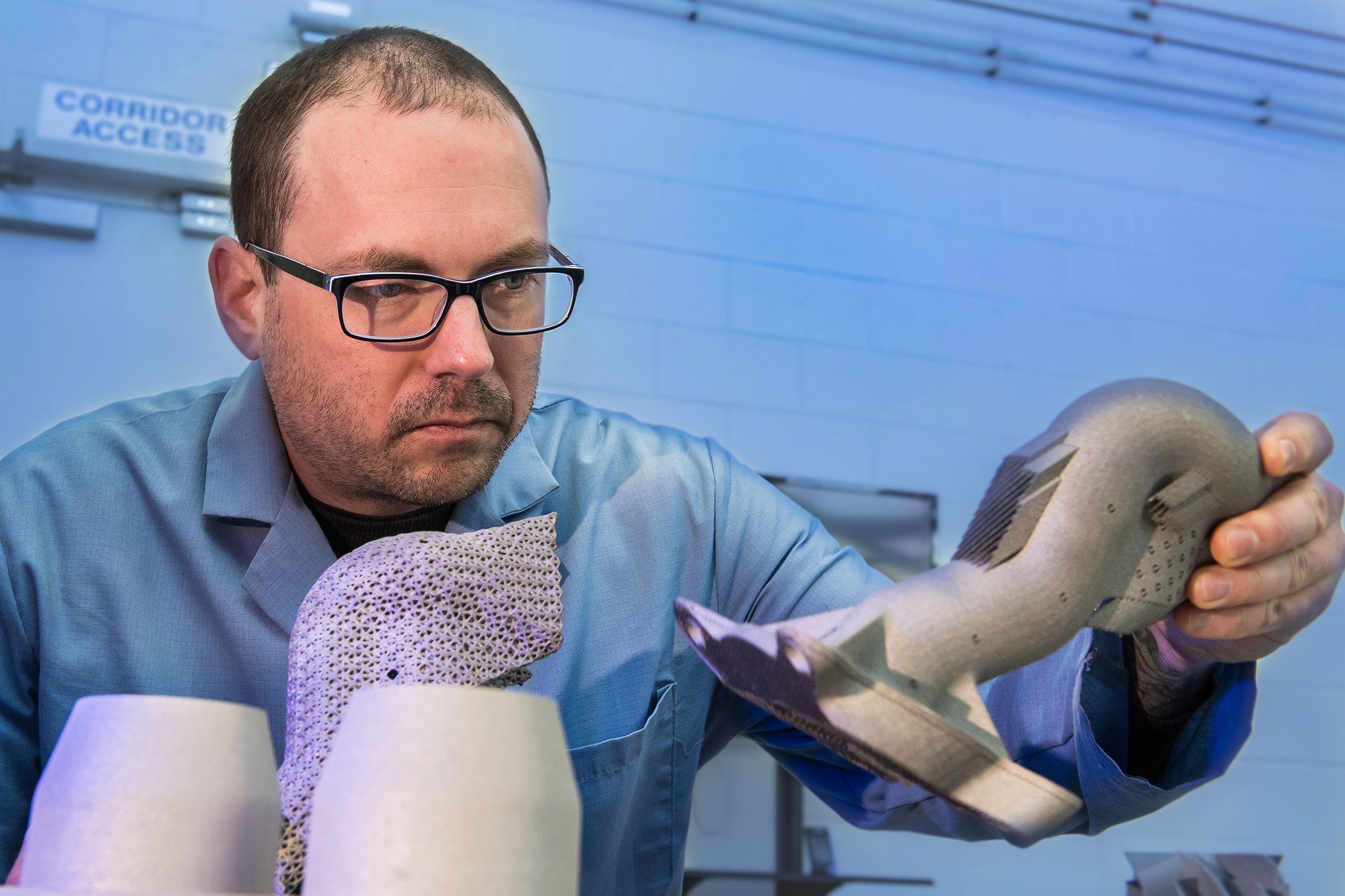 Army researcher Dr. Brandon McWilliams, holds a sample 3D metal printed part. Photo via the U.S. Army/ David McNally.