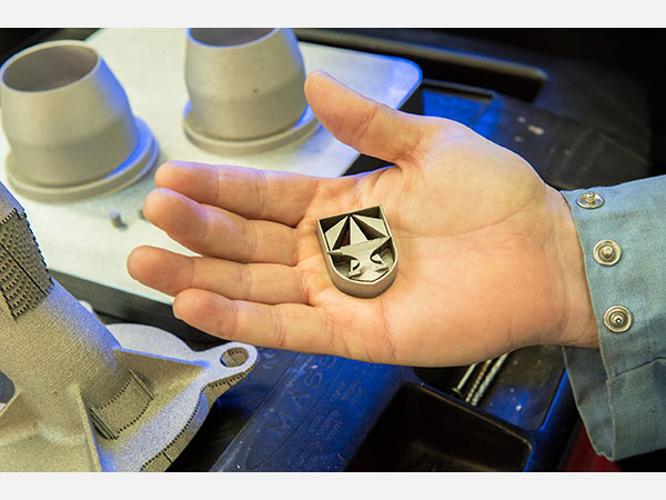 A 3D printed metal part testing the capabilities of custom alloys. This part shows the geometric capabilities of 3D printing with the symbol of the newly formed Army Futures Command. Photo via the U.S. Army/David McNally.