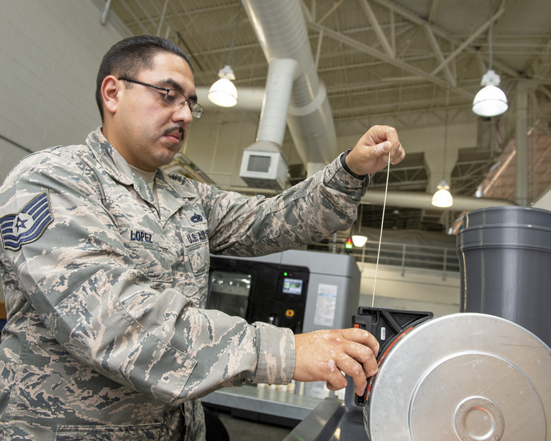 U.S. Air Force Tech. Sgt. Rogelio Lopez, 60th Maintenance Squadron assistant aircraft metals technology section chief, loads Ultem 9085 material for Stratasys F900. Photo via U.S. Air Force photo/Louis Briscese.
