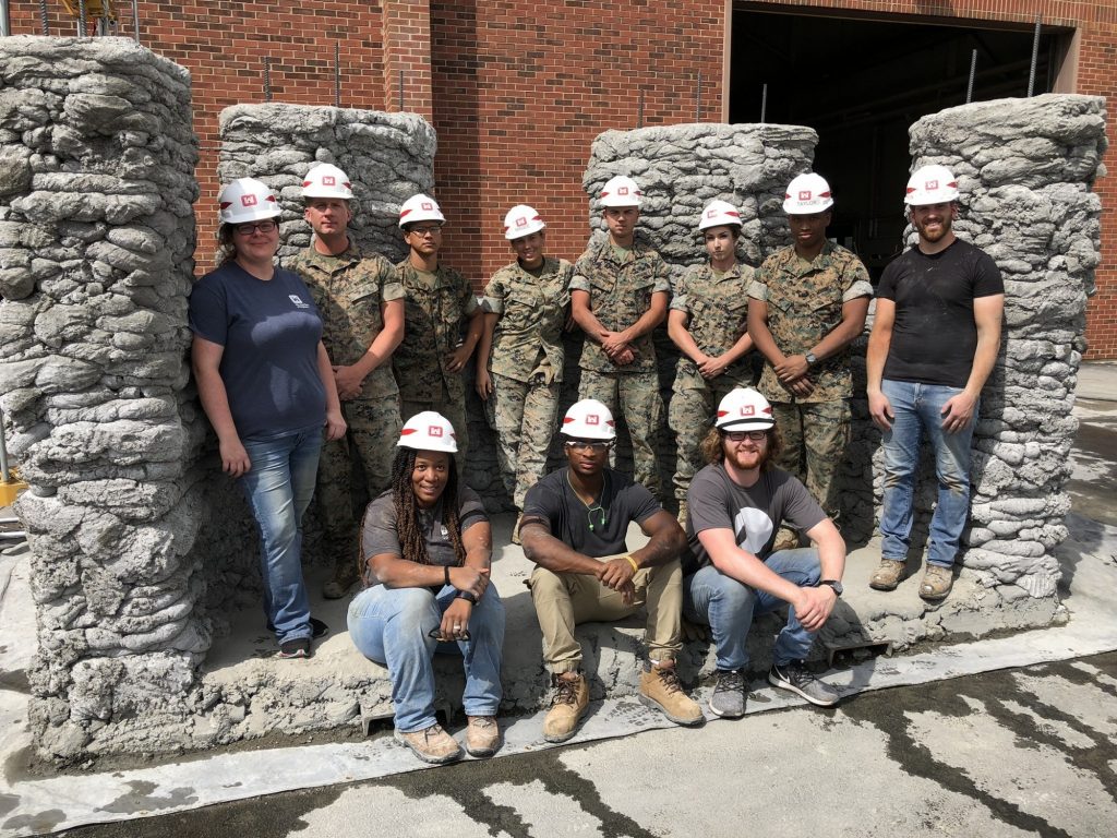 Marines from 7th Engineer Support Battalion along with engineers from the U.S. Army Corps of Engineers Construction Engineering Research Laboratory pose with a concrete bunker during a 3D concrete printing exercise. Photo via U.S. Marines/Staff Sgt. Michael Smith, 7th ESB.