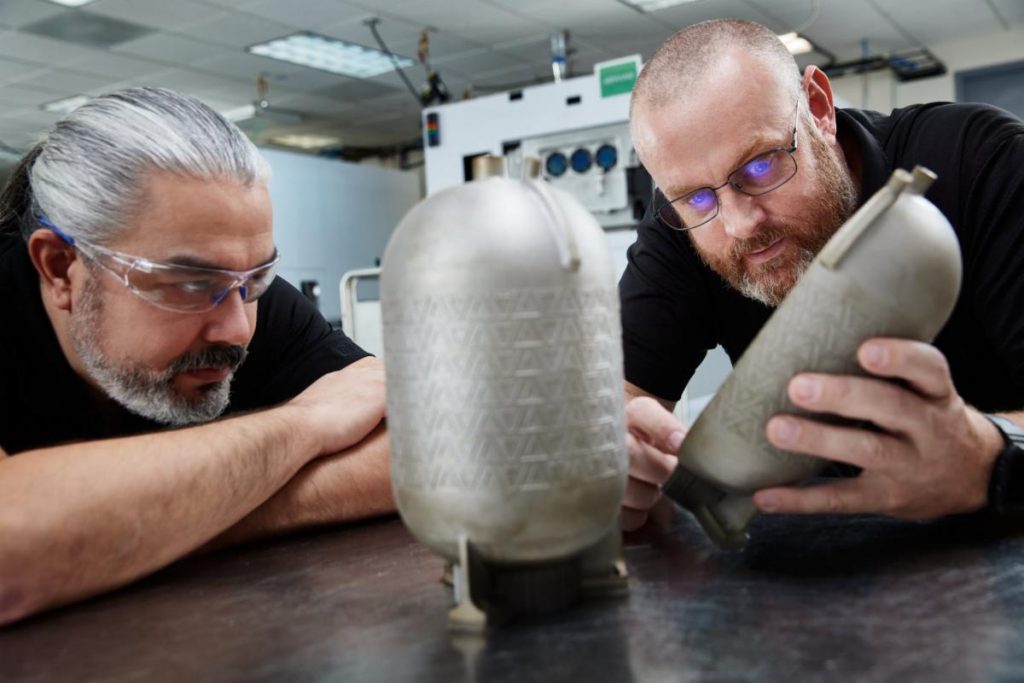 Engineers examine a titanium fuel tank printed on a VELO3D additive manufacturing system with no internal supports. Such tanks/pressure vessels are designed for use in aerospace and defense applications. Photo via VELO3D.