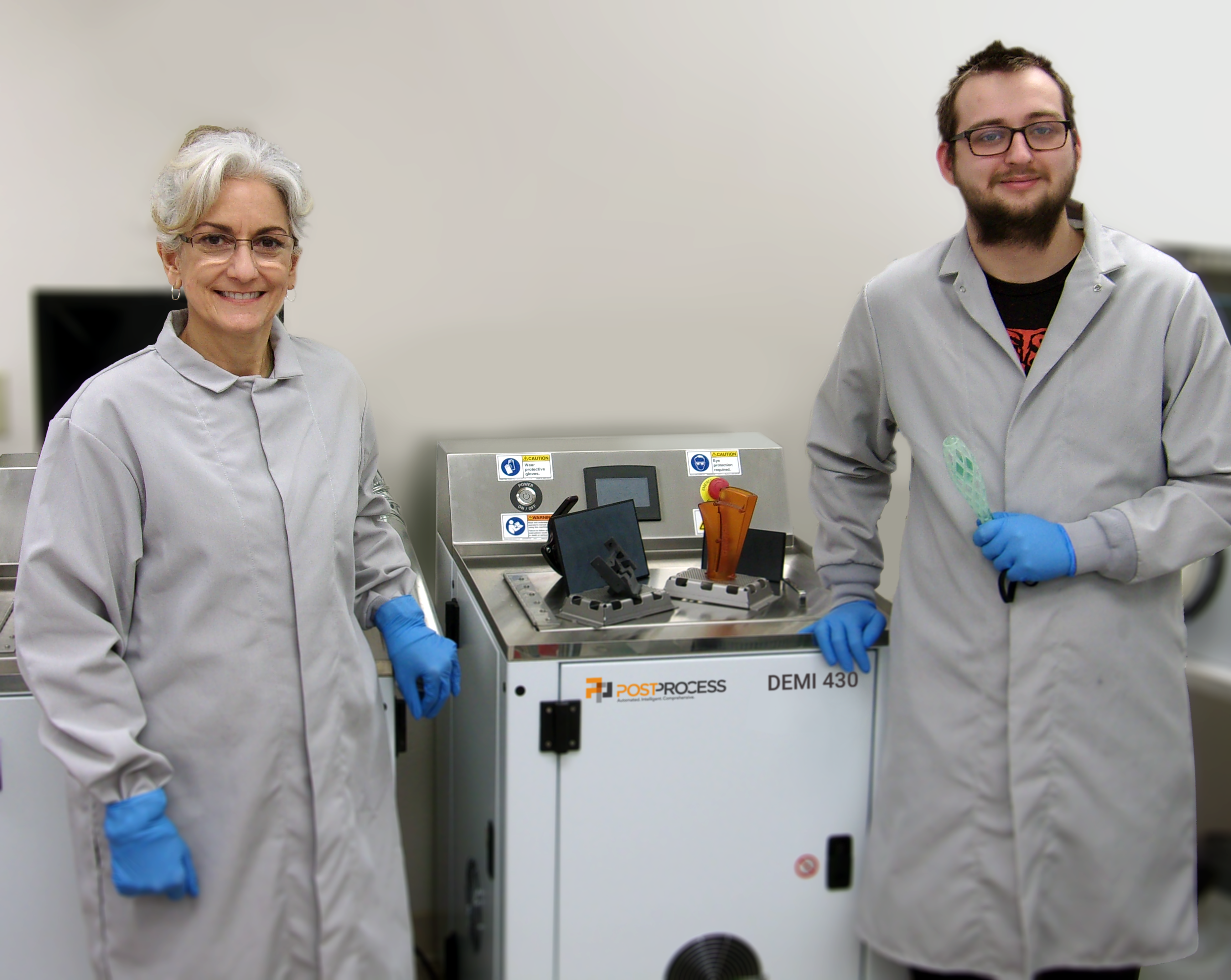 Primary Manufacturing lab technician Lisa Baker and engineering technician Gage Tift with the PostProcess DEMI 430 system. Photo via PostProcess Technologies.