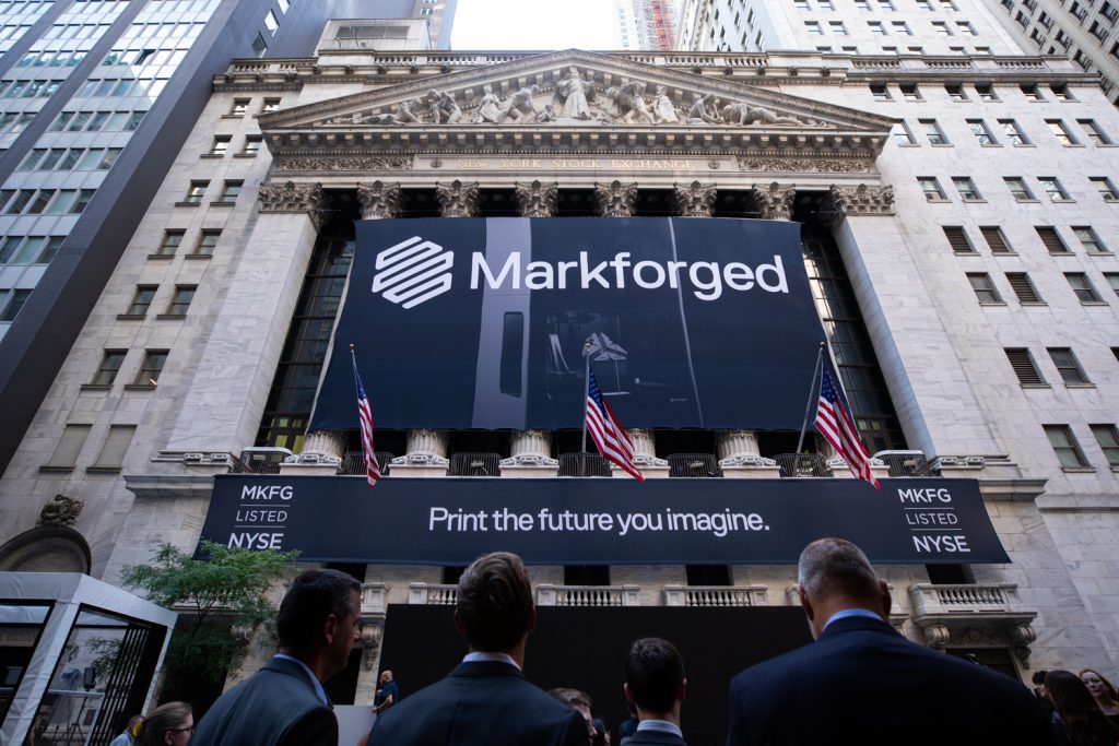 Traders look at a Markforged sign outside the NYSE.