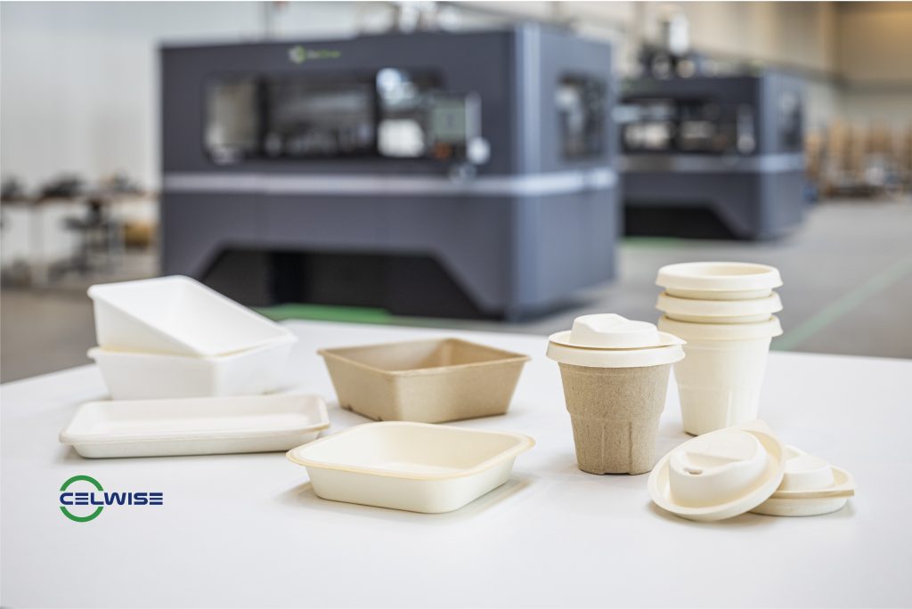 Celwise's sustainable molded fiber products, which replace single-use plastics, in front of the X1 160Pro production metal 3D printer. Photo via ExOne.