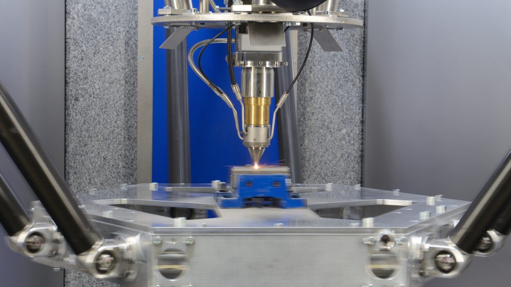 The tripod kinematics in action: stationary powder feed nozzle and moving build platform for the execution of fast and precise feed movements. Photo via Fraunhofer ILT.