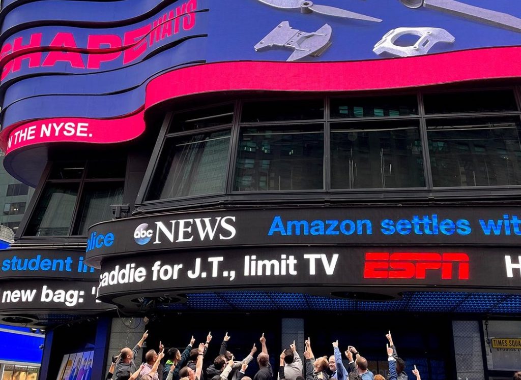 L'équipe Shapeways pointant vers le logo de l'entreprise à l'extérieur du NYSE.
