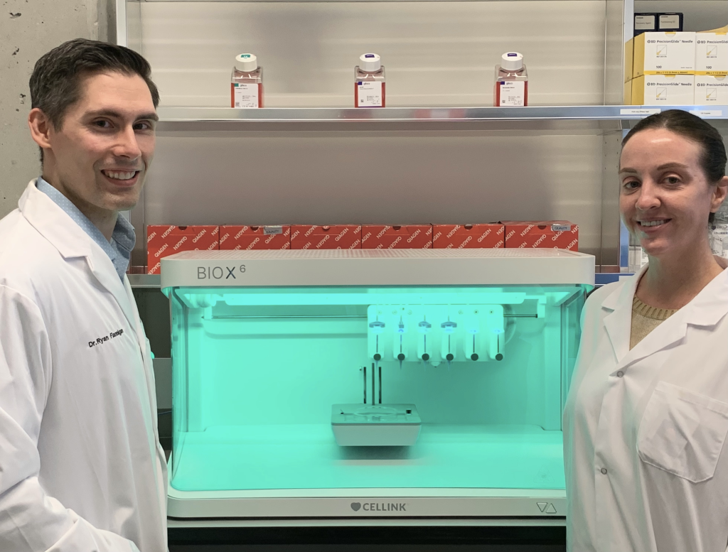 Dr. Ryan Flannigan and research assistant Meghan Robinson next to a CELLINK bioprinter. Photo via Ryan Flannigan.