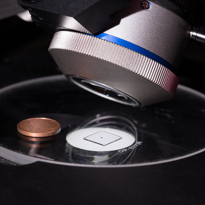 The researchers using a microscope to acquire images of a 600 micron 3D printed lens system. Photo via University of Stuttgart.