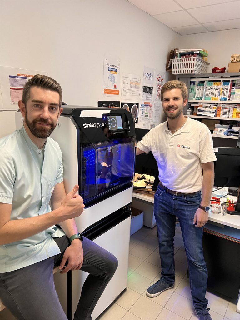 Samuel Guigo (à gauche), PDG du CHU de Brest avec l'imprimante 3D Stratasys J5 MediJet.  Image via Stratasys.