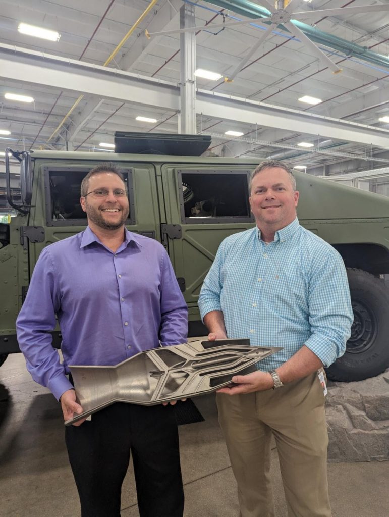 John Keogh (left), technical lead, and project manager Brad Friend hold a cut section of the 3D printed ramjet. Photo via LIFT