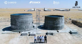 The world’s first on-site 3D printed large water tanks for chicken drinking water made for the Kuwait United Poultry Company. Representatives of Abyan, COBOD, and Kuwait United Poultry Company are seen in the front. Some chicken farms are seen at the top of the picture. Photo via Abyan.