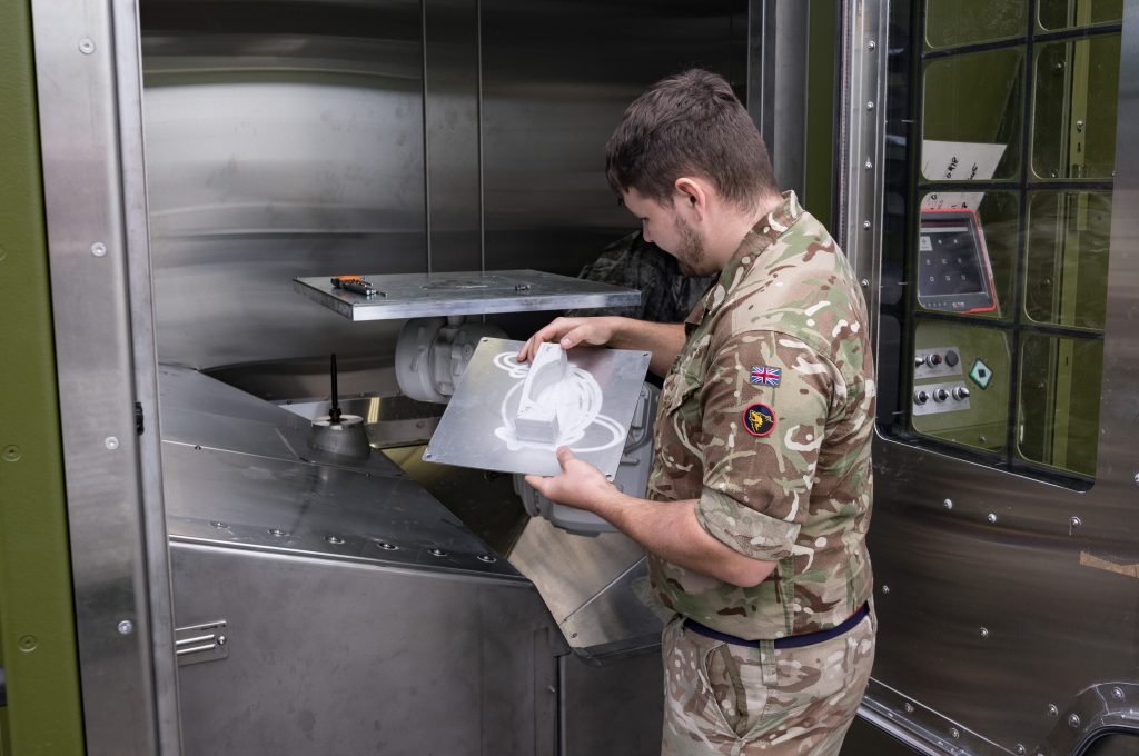 An operator checking the manufactured part after 3D printing is complete. Photo via the British Army.