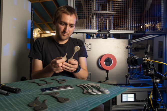Charlie Patterson of the James Watt School of Engineering examines samples of 3D printed material tested in the NextSpace TestRig. Photo via University of Glasgow.