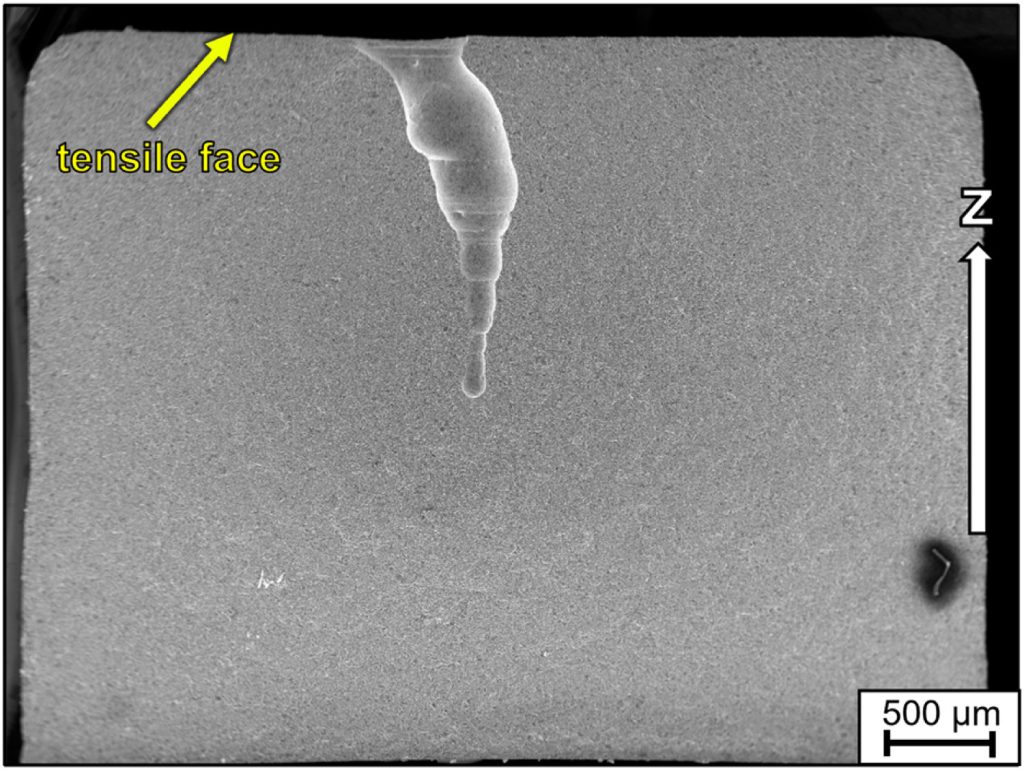 “Wormhole” formation due to pore coalescence in a bending bar, with the building direction z as indicated by the white arrow. Image via ScienceDirect.