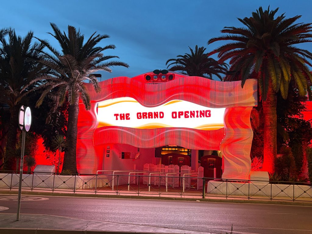 Fachada impressa em 3D para a Grande Inauguração 2025 da Pacha Ibiza, com módulos PLA brancos em forma de onda iluminados em vermelho. Foto via WASP.