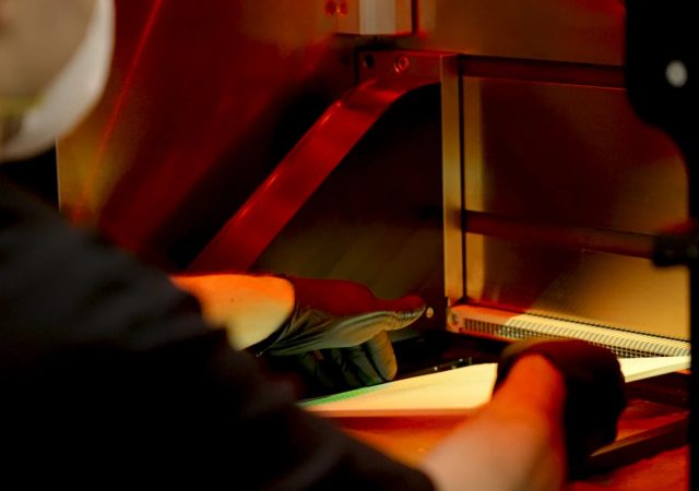An engineer handling a build plate inside a 3D printer. Photo via NASA.